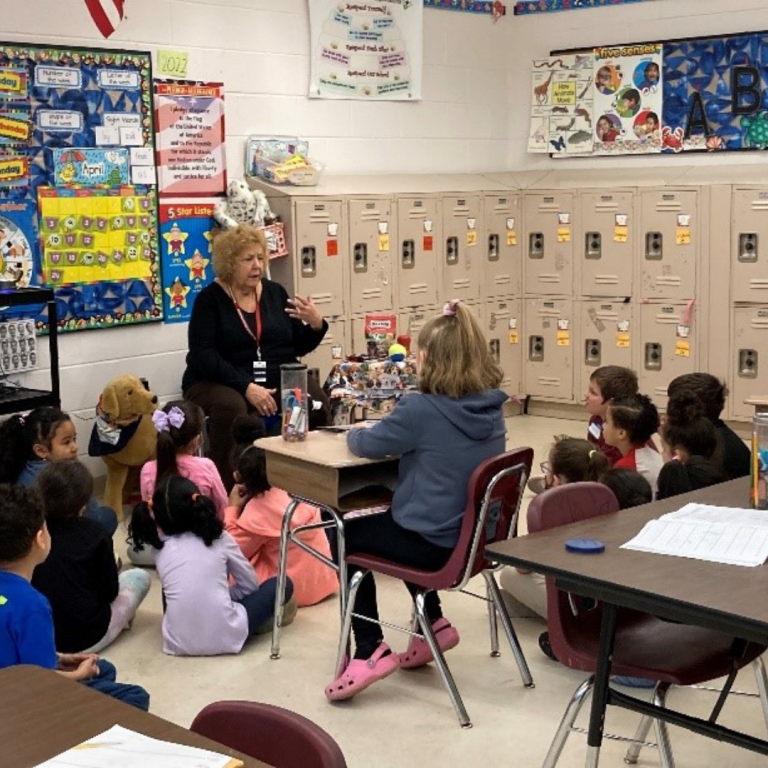 Human education sitting with a group of young students in a classroom to teach about animals