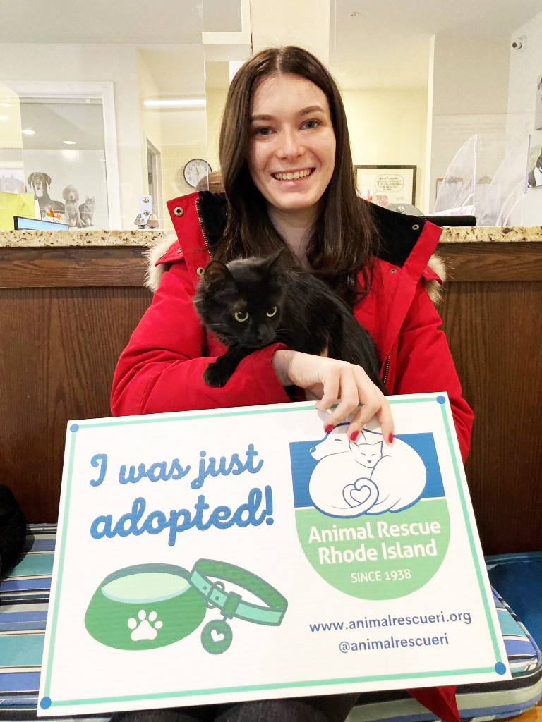 Young woman in red jacket adopts a small black kitty
